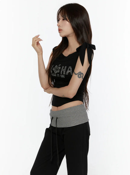 Graphic Off-Shoulder Top CL508 Black side model shot raised hand pose rhinestone ALOHA graphic bow-tie shoulder detail ruched waist cropped silhouette