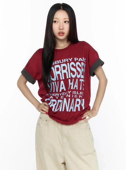 Graphic Oversized Layered Tee CL524 Red front shot on model hands on hips, light blue letter graphic print, dark gray cuffed sleeves, crew neck