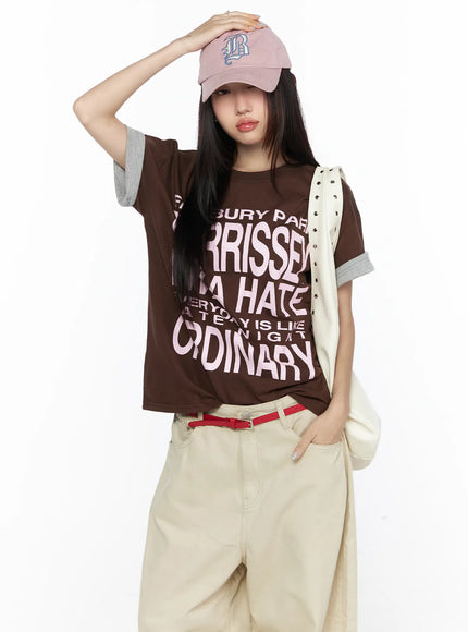 LEWKIN Graphic Oversized Layered Tee CL524 Brown front shot on model with pink cap and cream bag, pink letter print, gray cuffed sleeves, M/L