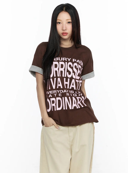 Graphic Oversized Layered Tee CL524 Brown half-body front shot on model direct gaze, pink graphic print, gray layered short sleeves, styled with beige wide trousers