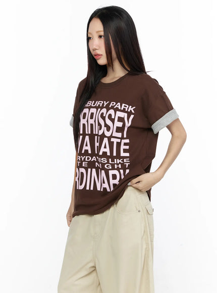 Graphic Oversized Layered Tee CL524 Brown three-quarter front shot on model hand on hip, pink Morrissey graphic print, gray layered cuffs, crew neckline detail