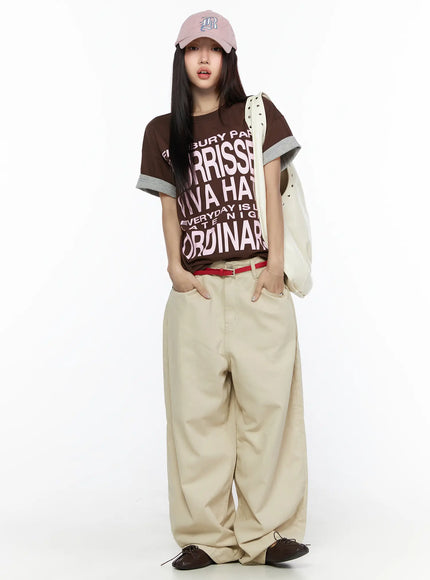 Graphic Oversized Layered Tee CL524 Brown full-body front shot on model with pink cap and white studded bag, pink letter graphic, red belt, street style outfit