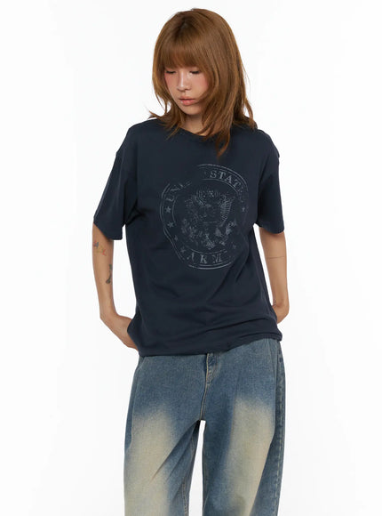 Graphic Oversized Tee CL503 Dark blue front shot on model looking downward, hands tucked in pockets, relaxed oversized fit with wide-leg denim