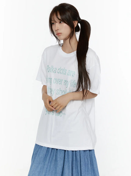 Graphic Oversized Tee CL508 White front three-quarter view on model with ponytail, mint green polka dot letter print on oversized cotton tee styled with denim skirt