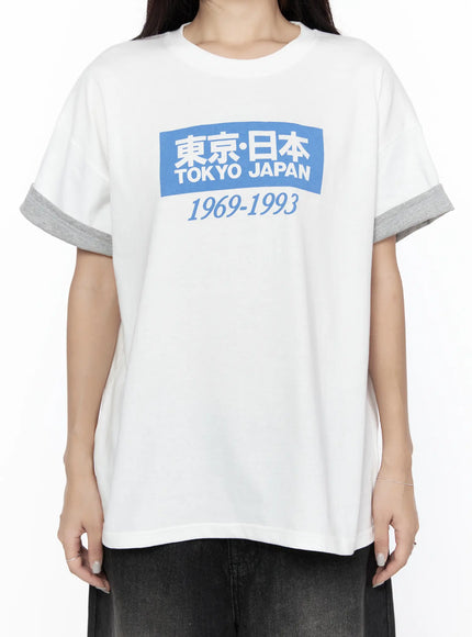 Graphic Oversized Tee CL527 White close-up front on model showing blue box Tokyo Japan 1969-1993 graphic print and gray contrast rolled sleeve cuffs