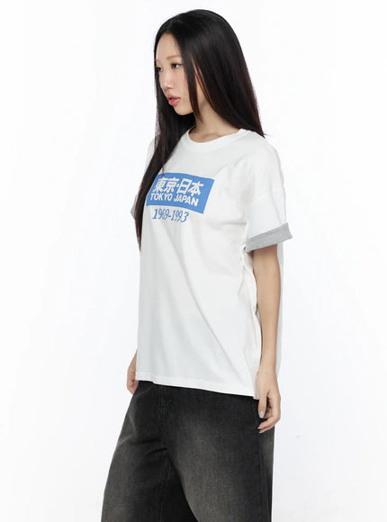 Graphic Oversized Tee CL527 White side close-up on model angled right showing blue Tokyo Japan box graphic print and gray contrast cuff sleeve detail