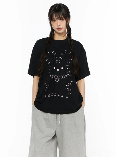 LEWKIN Graphic Oversized Tee CU530 Black front view on model wearing twin braids and gray sweatpants, oversized cotton tee with dot-to-dot bear face and heart necklace pink print