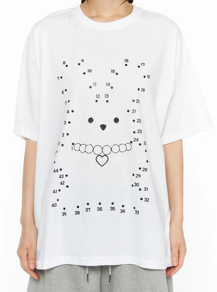 Graphic Oversized Tee CU530 White close-up front shot on model showing numbered dot-to-dot bear face with heart charm necklace print detail on cotton fabric