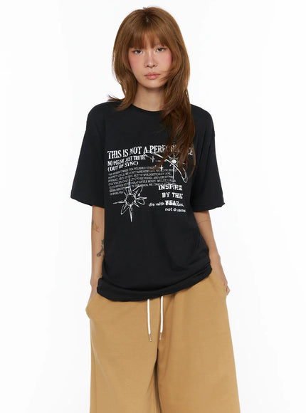 Graphic Oversized Top CL503 Black front shot on model standing facing forward with grunge star graphic print styled with tan drawstring pants