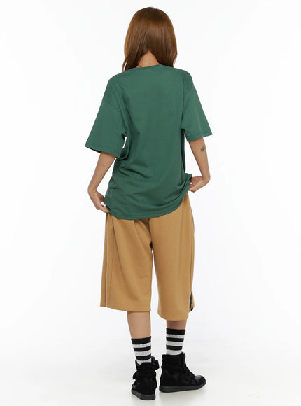 Graphic Oversized Top CL503 Green back shot on model showing plain clean back panel dropped shoulder seams and oversized fit styled with tan bermuda shorts