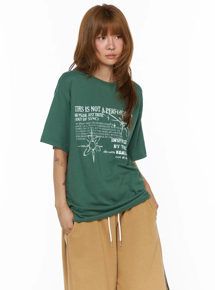 Graphic Oversized Top CL503 Green three-quarter front shot on model showing oversized boxy silhouette with grunge graphic print styled with tan wide-leg pants