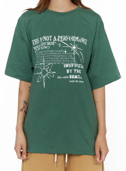 Graphic Oversized Top CL503 Green close-up front detail shot on model showing THIS IS NOT A PERFORMANCE white grunge text and star graphic print on cotton