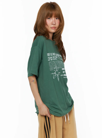 Graphic Oversized Top CL503 Green diagonal side shot on model showing white grunge text graphic and star motif styled with tan striped-side shorts