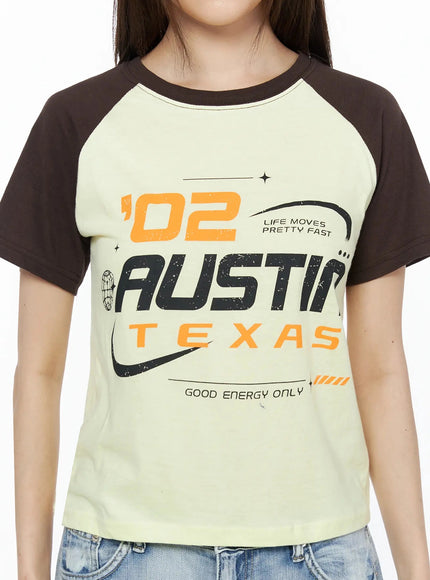 Graphic Print Color Block Tee IL523 Yellow close-up detail shot showing '02 Austin Texas Good Energy Only' graphic print with dark brown raglan contrast sleeves