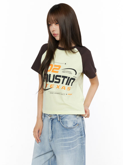 Graphic Print Color Block Tee IL523 Yellow three-quarter side-front shot on model with arm at side, dark brown raglan sleeves, graphic tee tucked loosely into jeans