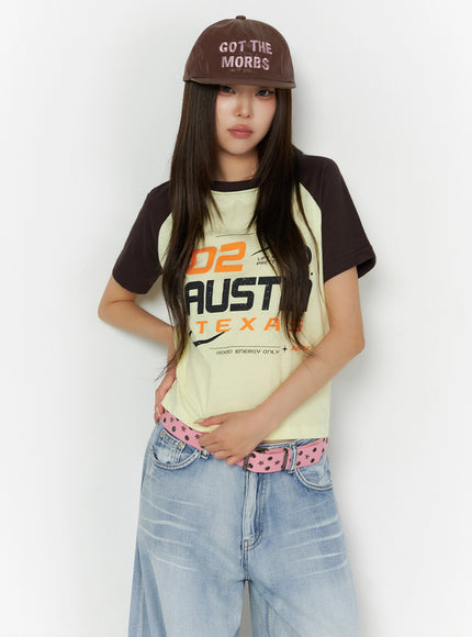 LEWKIN Graphic Print Color Block Tee IL523 Yellow front shot on model wearing brown cap, pink star belt, wide-leg jeans, hands clasped