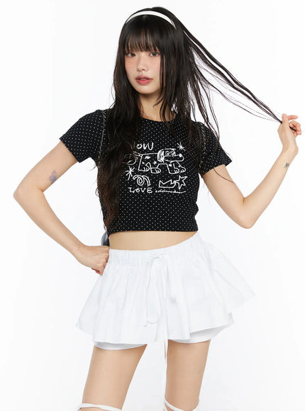LEWKIN Graphic Print Crop Tee CU530 Black S/M front view on model hand in hair wearing white mini skirt white polka dot crop tee