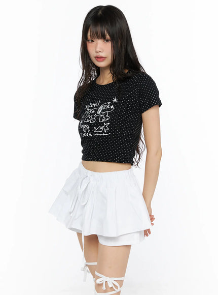 Graphic Print Crop Tee CU530 Black side shot on model showing white polka dot texture crop length short sleeves and cropped hem above waist