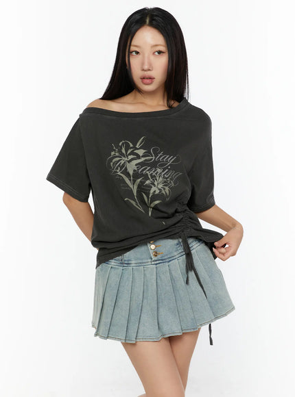Graphic Print One-Shoulder Oversized Tee CU529 dark gray front model shot hand on hip, off-shoulder neckline, lily print, ruched side drawstring, paired with denim mini skirt