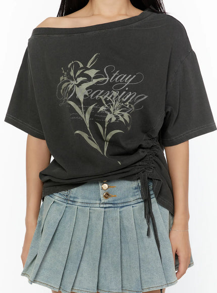 Graphic Print One-Shoulder Oversized Tee CU529 dark gray close-up front model shot showing Stay Dreaming lily graphic print and side ruched drawstring hem detail