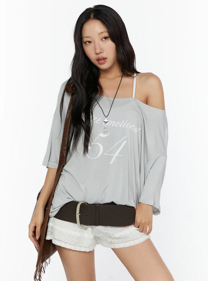 LEWKIN Graphic Print Oversized Tee CU529 Light gray front shot on model styled off-shoulder with brown fringe bag and lace shorts