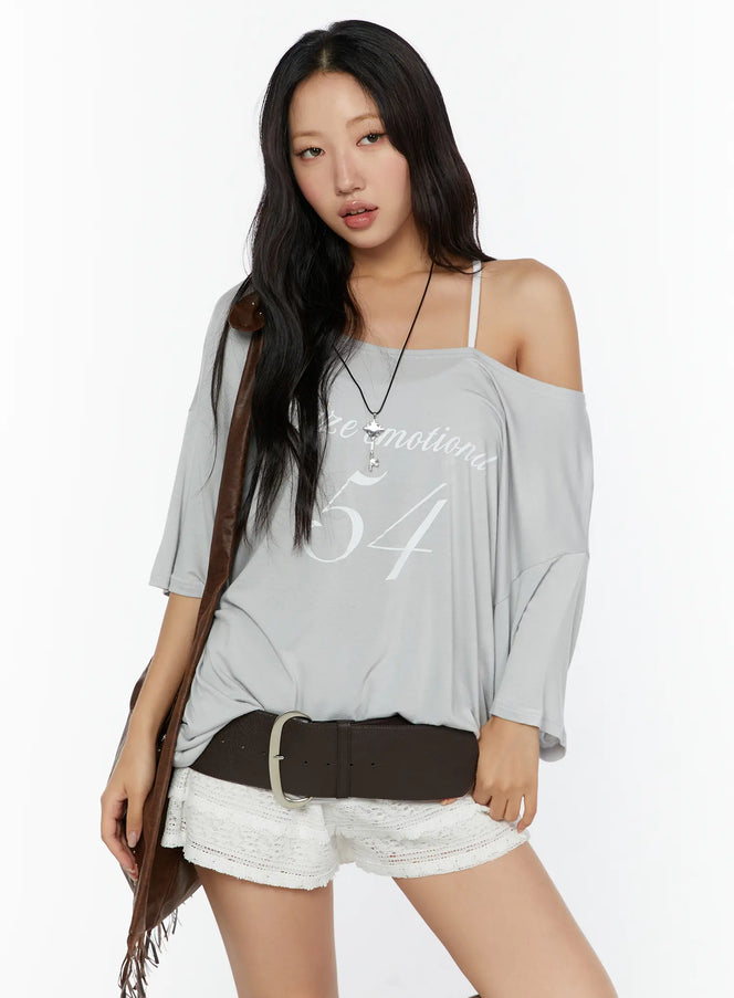 LEWKIN Graphic Print Oversized Tee CU529 Light gray front shot on model styled off-shoulder with brown fringe bag and lace shorts