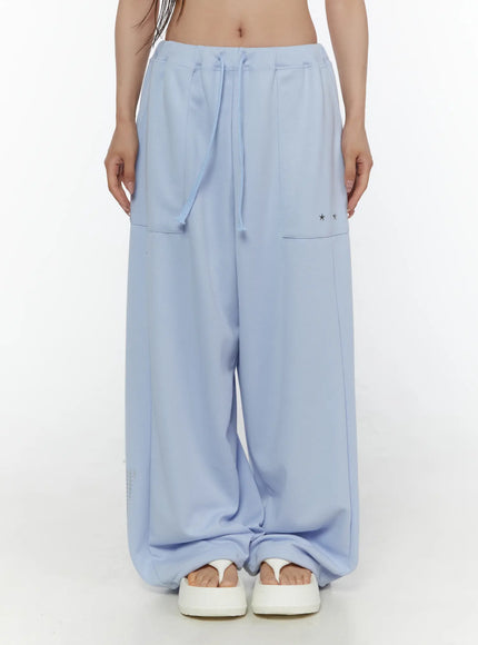 Graphic Print Wide Sweatpants CL507 light blue front close-up shot on model showing drawstring waist star studs cargo pocket and pooling hem