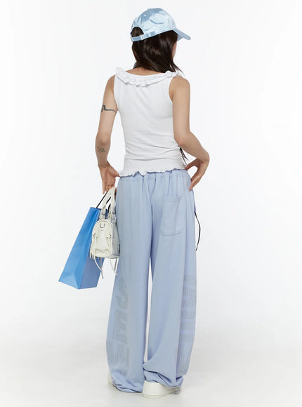 Graphic Print Wide Sweatpants CL507 light blue back shot on model styled with white ruffle crop top and blue cap holding shopping bags