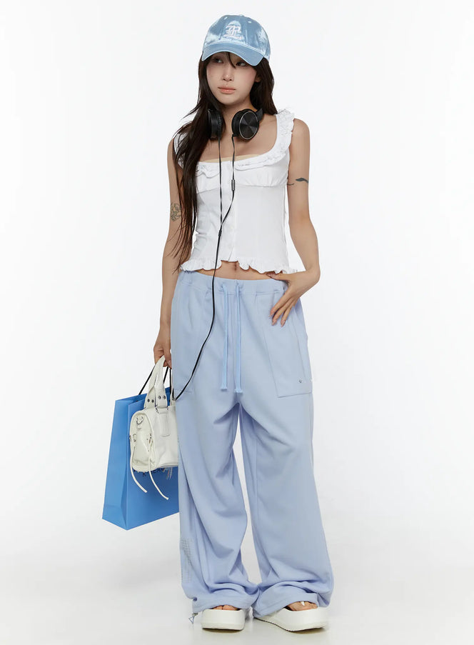 LEWKIN Graphic Print Wide Sweatpants CL507 light blue front shot on model standing with hand on hip styled with white crop top and cap