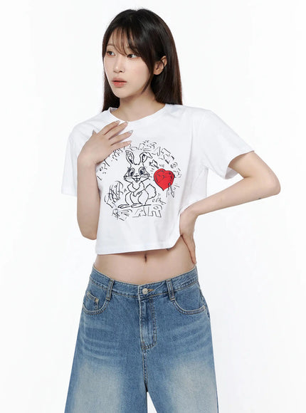 Graphic Rabbit Crop Top IL502 White front shot on model hand on chest highlighting rabbit heart graphic print and relaxed crop silhouette