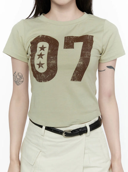 Graphic Retro Print T-Shirt IL522 Dark green close-up front on model highlighting distressed brown 07 numeral and three-star graphic on sage cotton tee