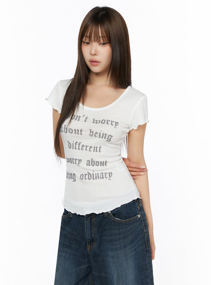 Graphic Scoop Neck Top IL523 White front close-up on model showing rhinestone gothic letter print, scoop neckline, flutter sleeves, and lettuce hem detail