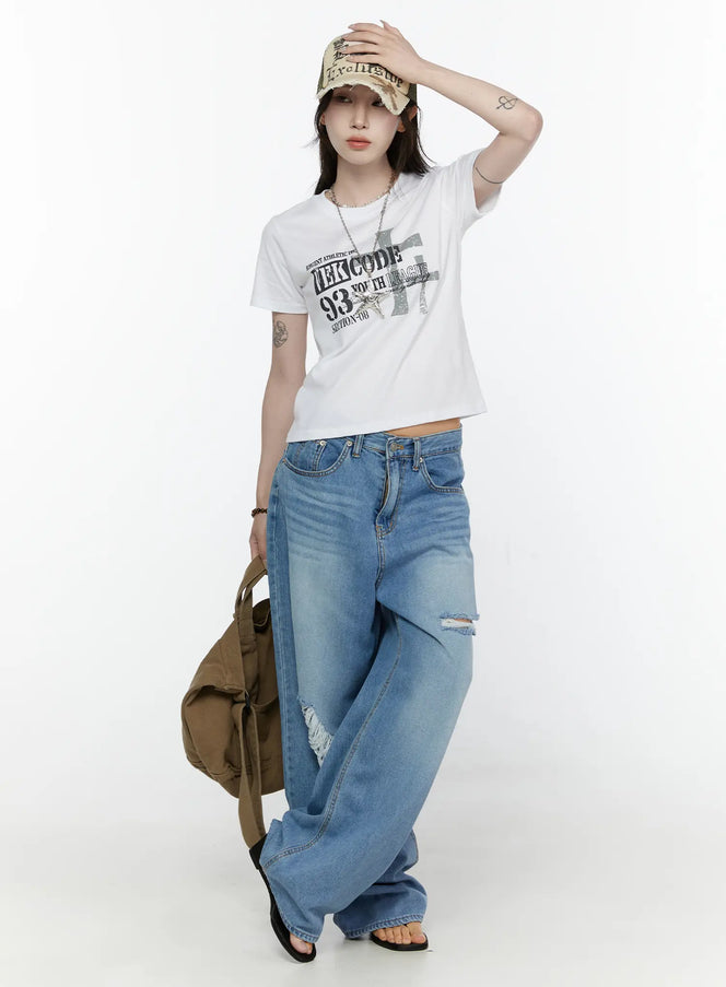 LEWKIN Graphic Semi-Crop T-Shirt IL522 White front full-body shot on model wearing cap, styled with ripped wide-leg jeans and canvas tote bag