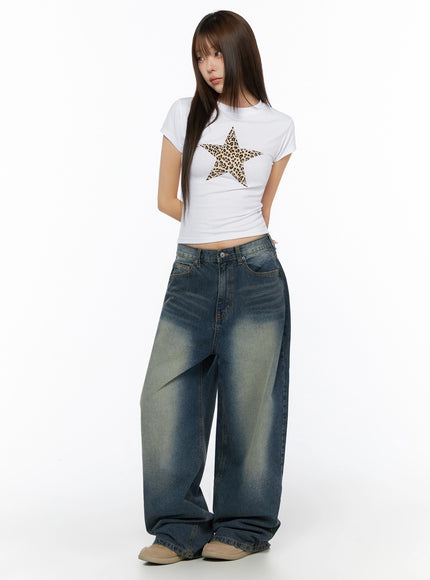 Graphic Short Sleeve T-Shirt IL523 White angled full-body model shot showing leopard star graphic on fitted crop tee with hands behind back and wide-leg jeans