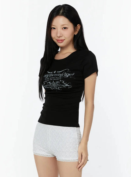 Graphic Short Sleeve Tee IU524 Black three-quarter side smiling model shot showing slim crop fit and gothic print, paired with lace shorts