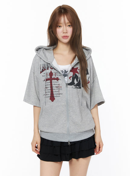 Graphic Short Sleeve Zip-Up Hoodie IU525 Gray front view on model standing, red cross and LEEFOREN graphic print, zip-up closure, styled with black ruffle mini skirt and white inner top