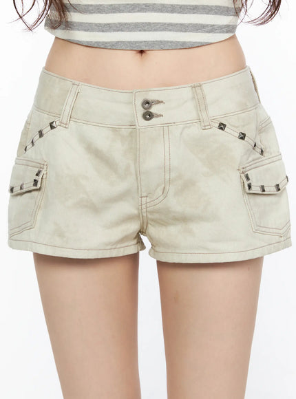 Graphic Studded Cargo Cotton Shorts CL522 Light beige close-up front shot on model highlighting silver pyramid studs along pocket trim and double buttons