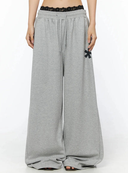 Graphic Sweatpants IL509 Gray front model shot cropped view showing elastic drawstring waistband with black lace bralette peeking above and asterisk graphic print on thigh