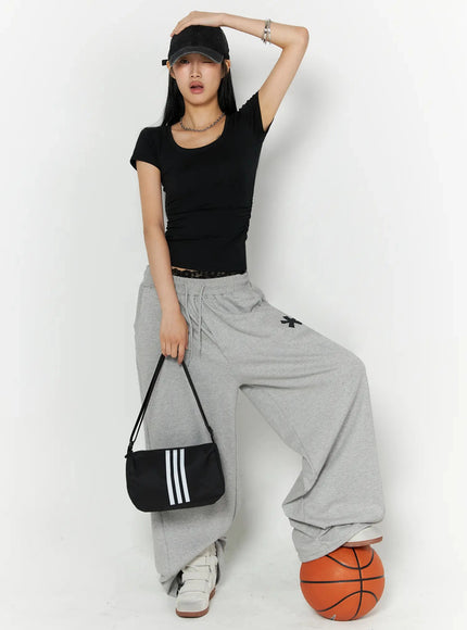 Graphic Sweatpants IL509 Gray full-length front model shot styled with black crop tee cap and shoulder bag wide-leg silhouette with asterisk print and basketball prop