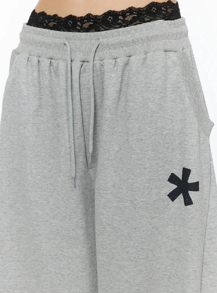 Graphic Sweatpants IL509 Gray close-up detail of waistband showing elastic drawstring construction black lace bralette waistband layering and asterisk print on front thigh