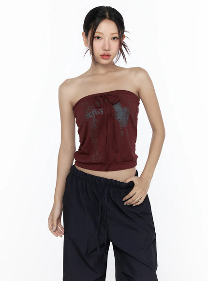Graphic Tube Top CL527 Dark red front model shot half-body pose with graphic print tie detail model facing forward hand on hip styled with black cargo pants