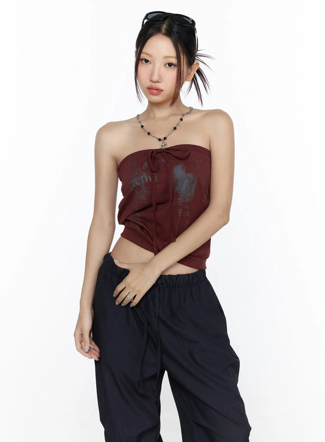 LEWKIN Graphic Tube Top CL527 Dark red front model shot cropped three-quarter pose with graphic print tie detail styled with chain necklace and black cargo pants