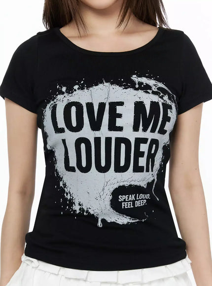 Graphic U-Neck Tee IL523 Black close-up detail on model showing LOVE ME LOUDER silver splash graphic print and scoop neckline, SPEAK LOUD FEEL DEEP sub-text