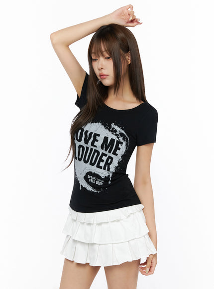 Graphic U-Neck Tee IL523 Black side-angle view on model with arm raised, short-sleeve fitted tee with LOVE ME LOUDER print, white tiered skirt styling