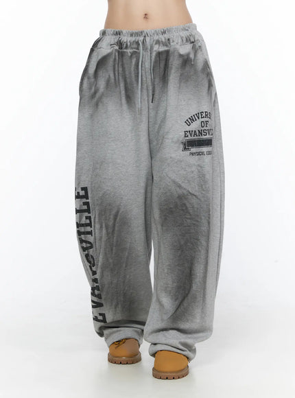Graphic Wide Leg Sweatpants CL527 Gray front shot on model showing wide-leg silhouette elastic waist collegiate logo print and slouchy hem detail