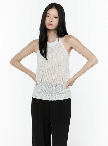 Halter Knit Top IL506 White front half-body shot on model hands on hips showing halter neckline semi-sheer open knit fabric and ribbed hem against black trousers