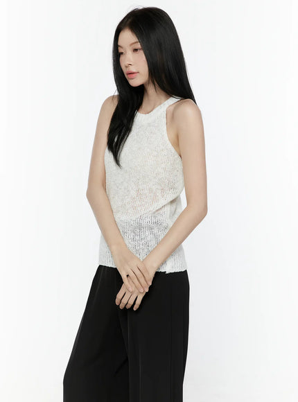 Halter Knit Top IL506 White side close-up shot on model hands clasped showing open knit texture semi-sheer fabric with ribbed hem and black trousers