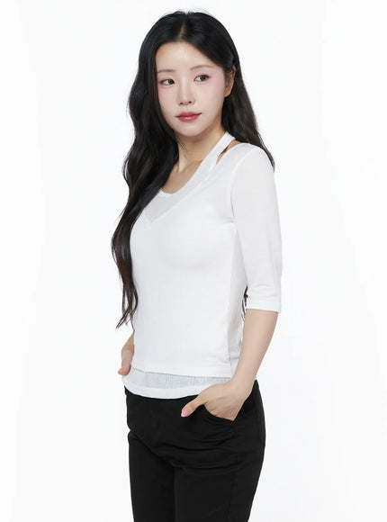 Halter Layered Three-Quarter Sleeve Top IU525 White side shot on model with wavy hair hands in pockets showing layered halter strap and ribbed hem with black trousers