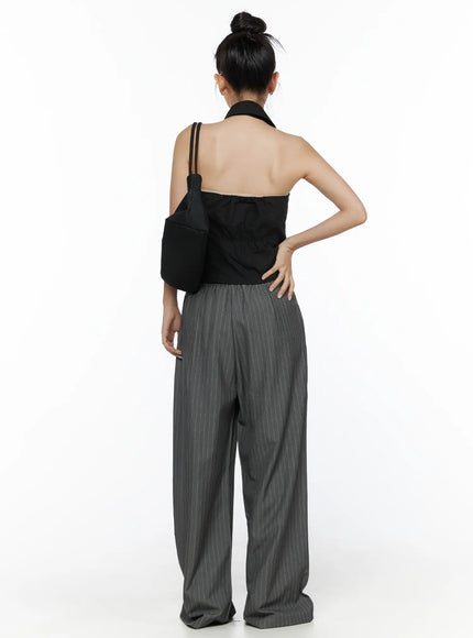 Halter Sleeveless Shirt CL510 Black back shot on model carrying black shoulder bag, open back design, halter collar tie detail, elastic waistband pants