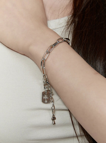 Haven Bold Heart Bracelet IL522 silver on-model wrist shot showing paper-clip chain with tag and cross charms dangling styled with white top